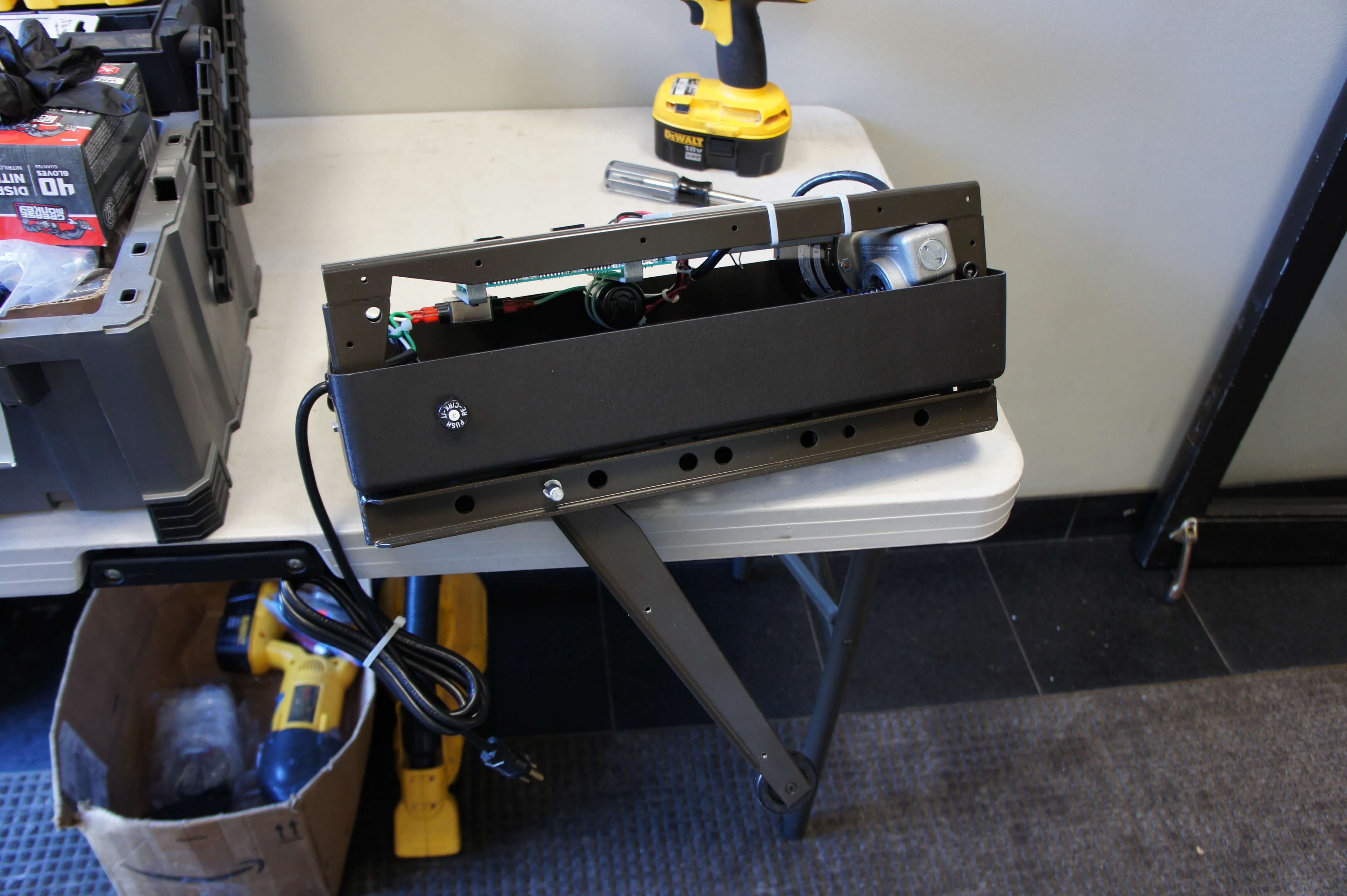 A Model 4300 Power Access automatic door opener with open arm on a work bench