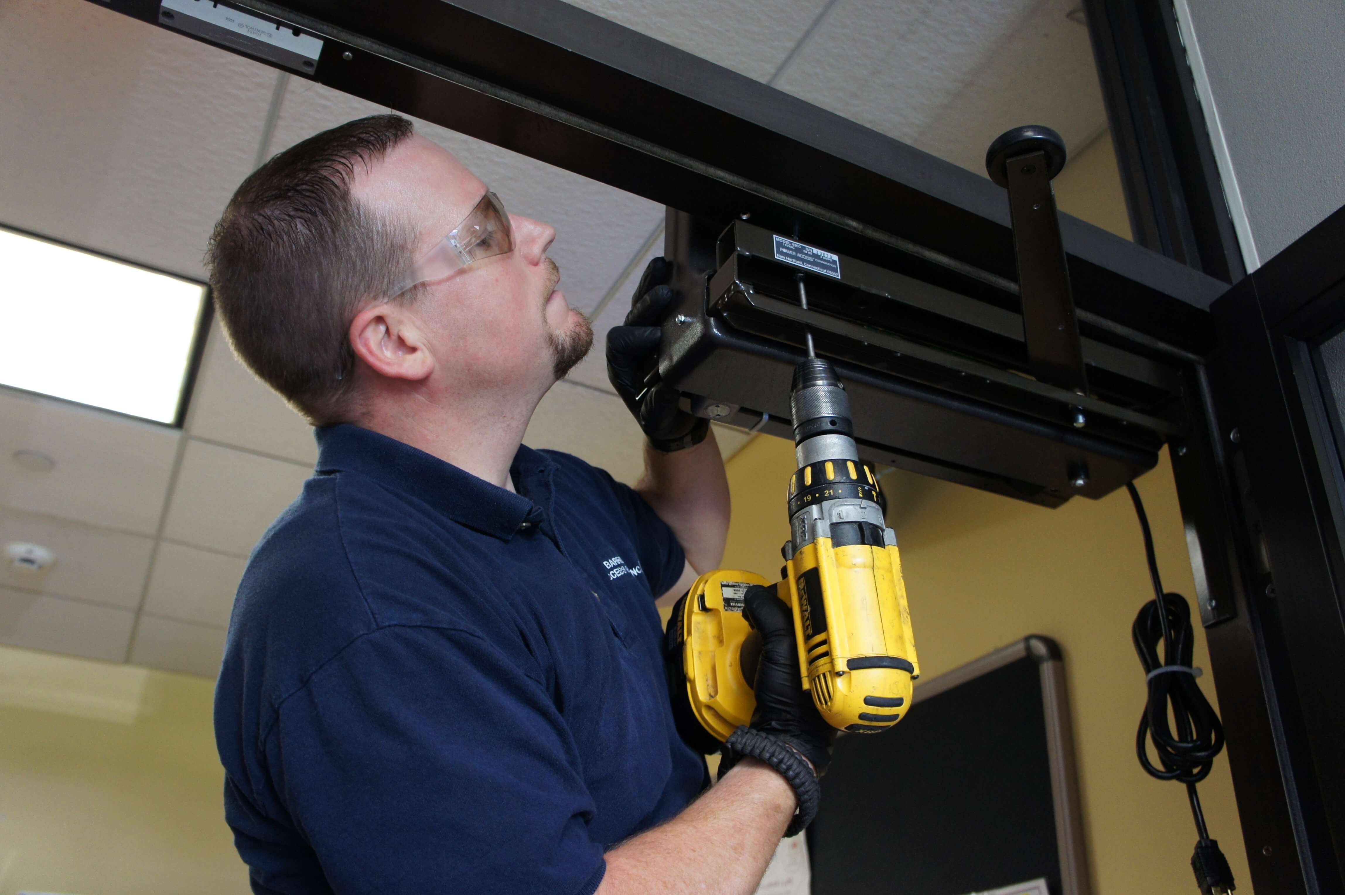 Man Securing the Model 4300 Power Access automatic door opener Onto door Frame Through Holes Underneath