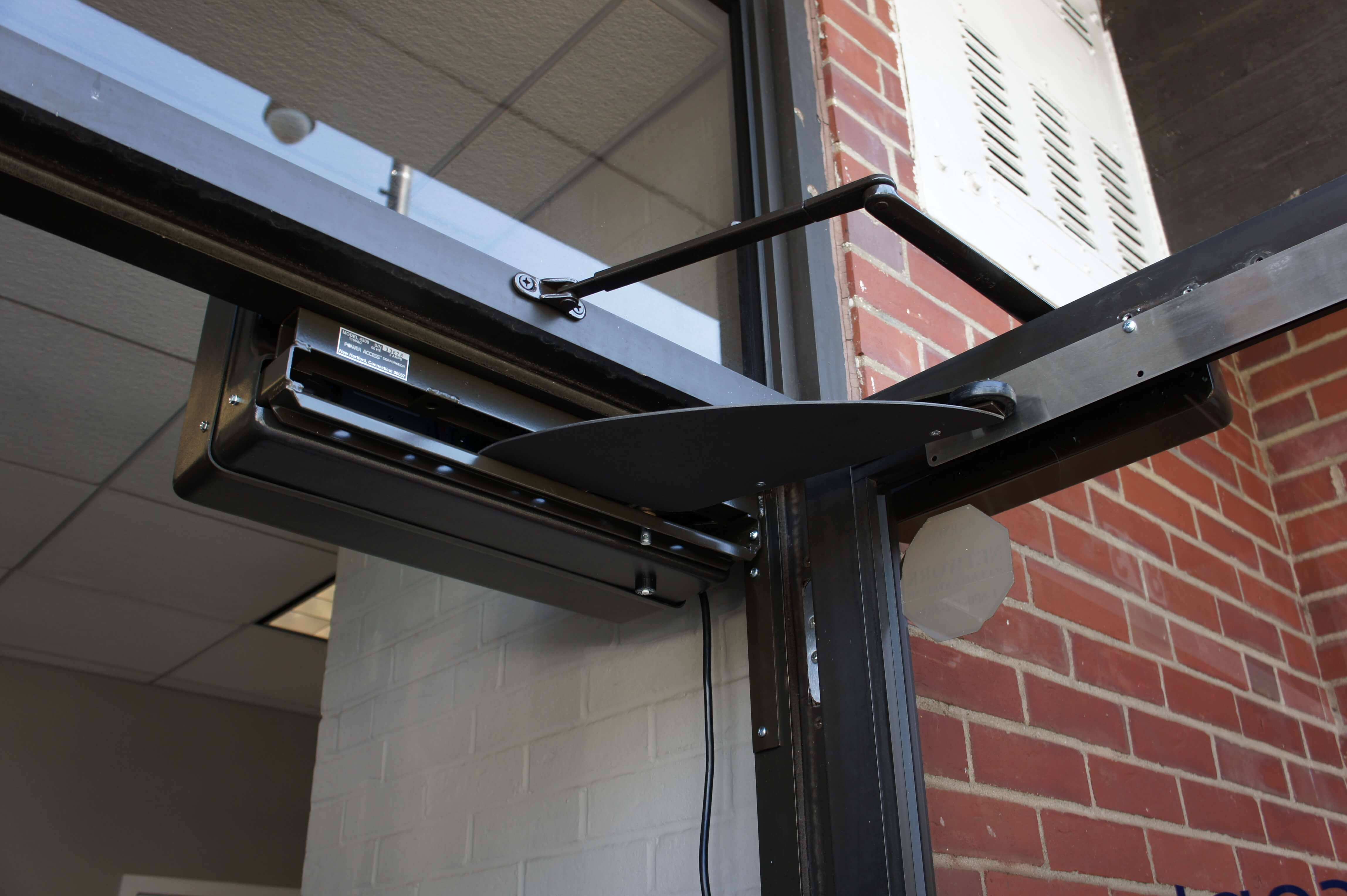 A Model 4300 Power Access automatic door opener in the open position with Finger Guard and Scuff Plate installed