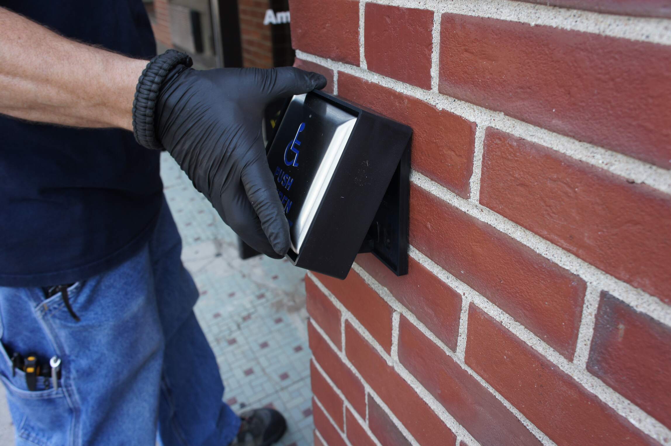 Man Installing Handicap accessible Wall Mount Push Plate on exterior of building