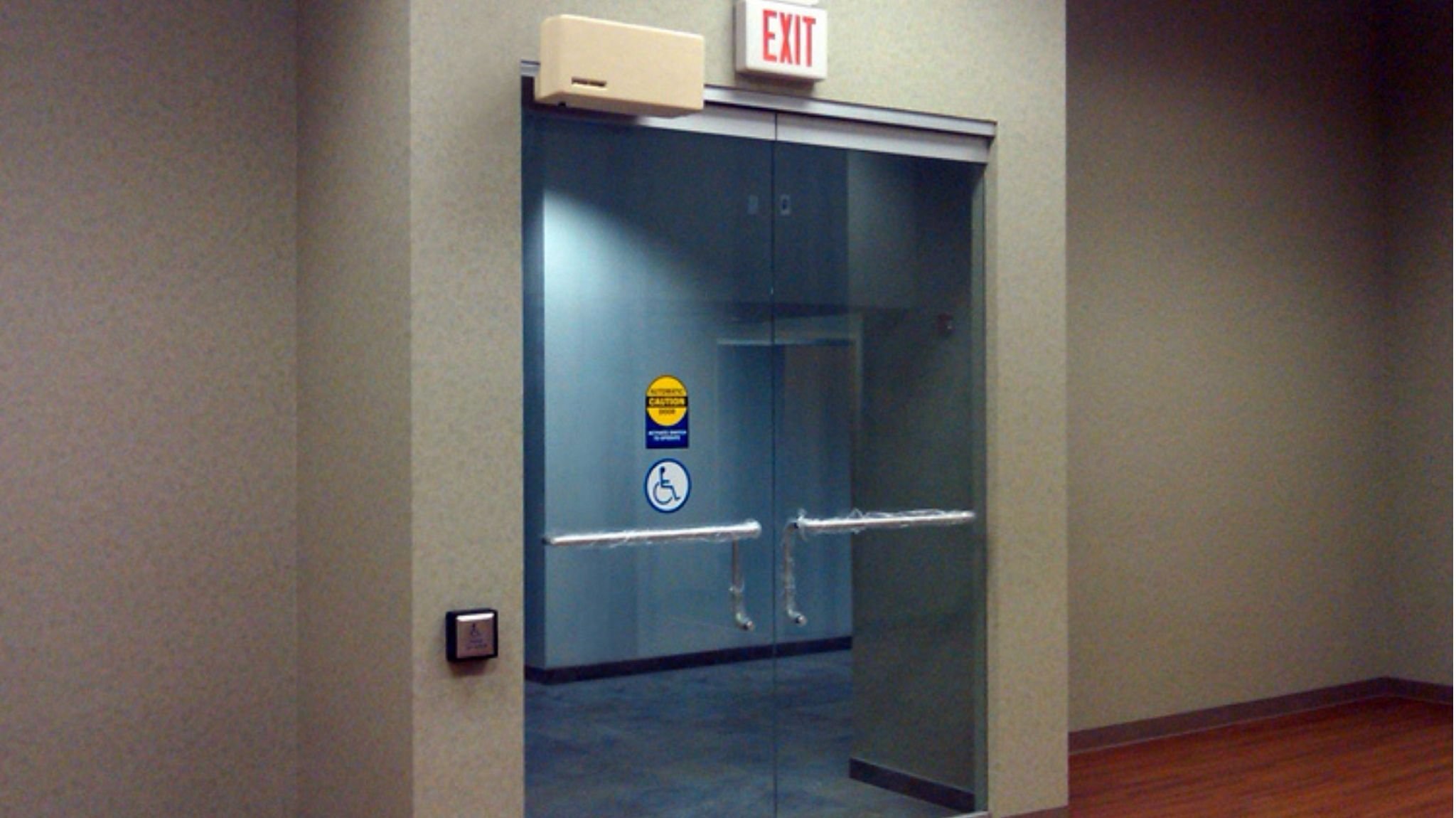 Model 4300L automatic door opener on an all glass door with push plate and accessibility stickers