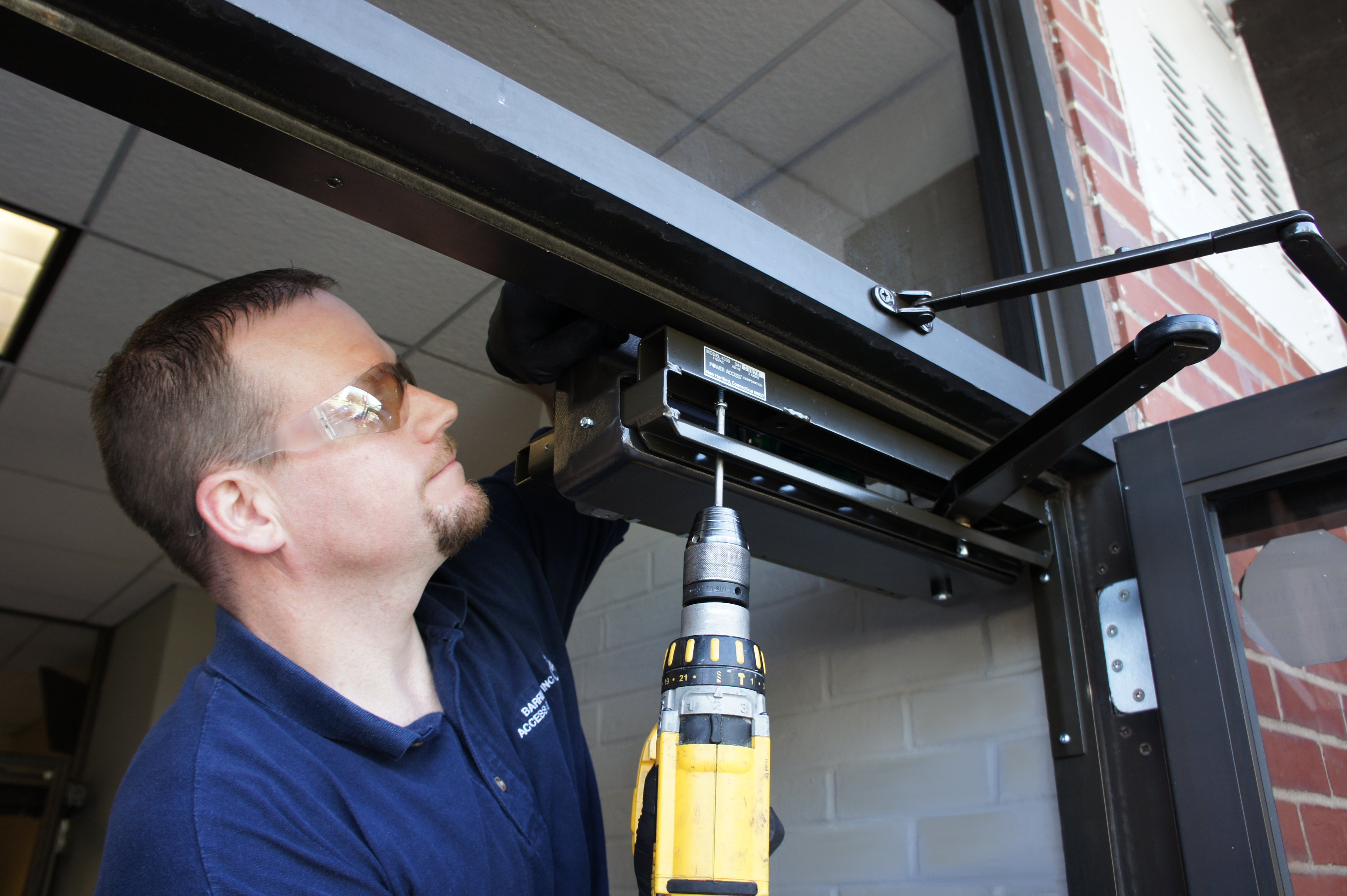 Man installing Model 4310L automatic door opener on exterior door
